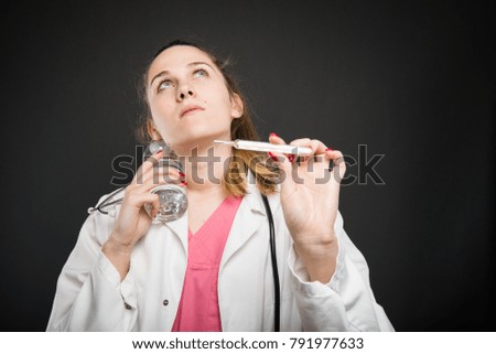 Female nutritionist cooling herself having fever holding thermometer on black background with copyspace advertising area