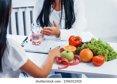 Female nutritionist gives consultation to patient indoors in the office. - Shutterstock ID 1596311923