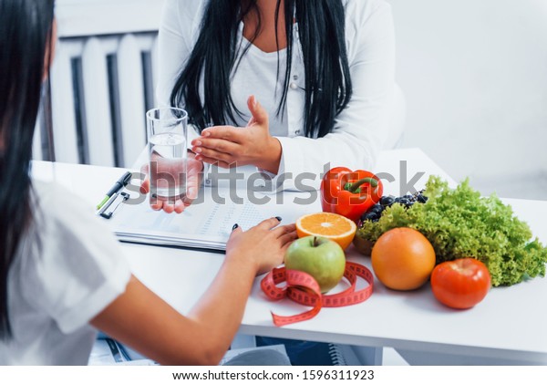 Female nutritionist gives consultation to patient indoors in the office.
