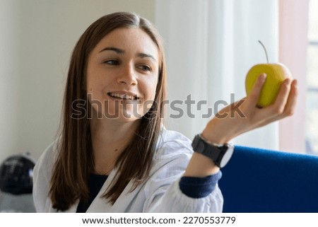Female nutritionist shows an apple. Healthy eating concept