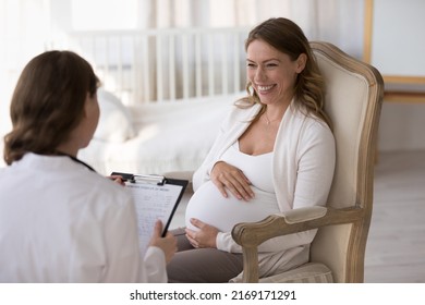 Female obstetrician gynaecologist filling medical form of pregnant woman at housecall appointment, doctor in uniform consults to expectant mom. Pregnancy, medicine, health-care, prenatal care concept