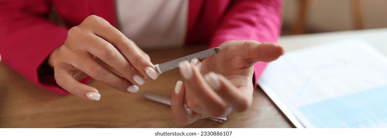 Female office manager filing her nails in office. Computer keyboard and financial report on office desk. Freelance business and breake time concept. - Powered by Shutterstock