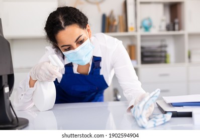 Female Office In Protective Mask Cleaner Is Cleaning Dust From The Desk In The Office