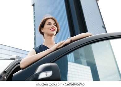 Female in office suit ariives at work by car and smiles