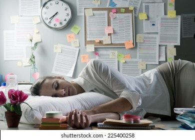 Female office worker bent over with head leaning to a wall and negative business chart.