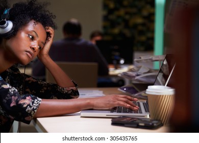 Female Office Worker With Coffee At Desk Working Late