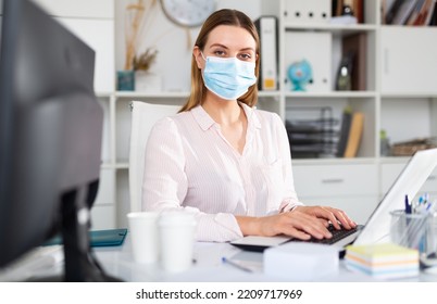 Female Office Worker In Protective Medical Mask Is Having Productive Day At Work In Office