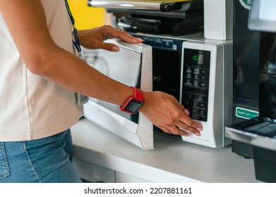 Female Office Worker In The Office Swithing On A Microwave Oven