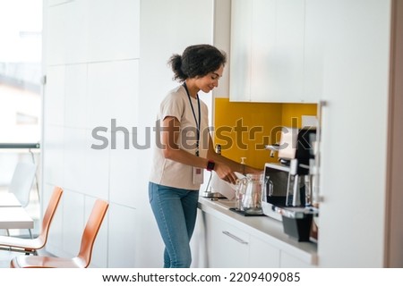 Female office worker in the office swithing on a microwave oven