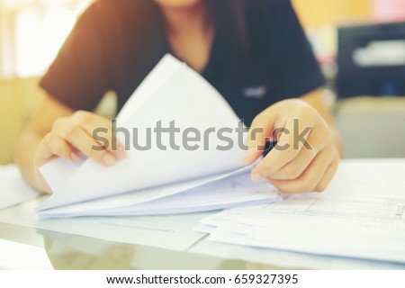 Female office workers holding  are arranging documents of unfinished documents on office desk, Stack of business paper.