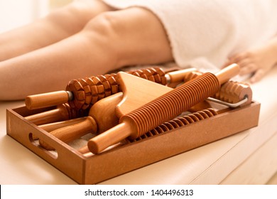 Female on  the massage table next to her is wooden massage tools for Maderotherapy.