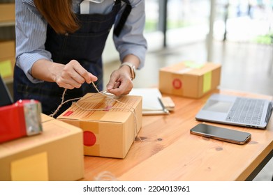 A Female Online Shop Owner Or Employee Packing A Shipping Package In Her Stock Room, Preparing Packages To Ship To Customers. Cropped Shot