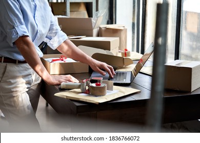 Female online store small business owner entrepreneur seller packing shipping ecommerce box checking website retail order using laptop preparing delivery parcel on table. Dropshipping concept. Closeup