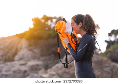 Female open water swimmer inflating her lifebuoy