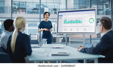 Female Operations Manager Holds Meeting Presentation for a Team of Economists. Asian Woman Uses Digital Whiteboard with Growth Analysis, Charts, Statistics and Data. People Work in Business Office. - Shutterstock ID 2109008447