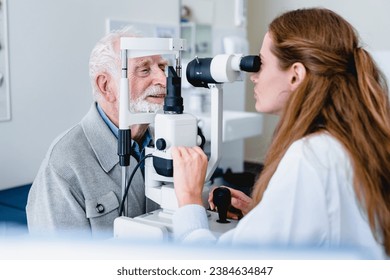 Female ophthalmic doctor diagnosing elderly patient`s sight using ophthalmic equipment, modern apparatus, slit-lamp, retinoscope for myopia cataract prevention