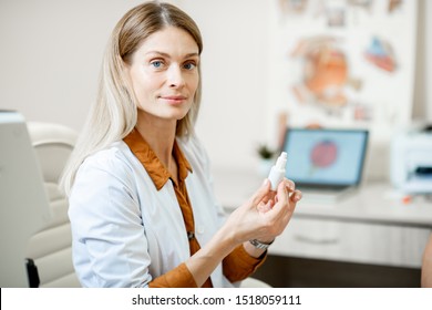 Female ophthalmologist with eye medicine in the dropper during medical consultation at the ophthalmologic office - Powered by Shutterstock