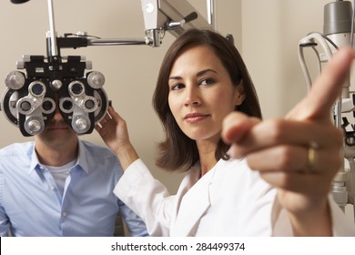 Female Optician In Surgery Giving Man Eye Test