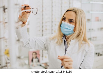 Female Optician Wearing Face Mask And Selling Glasses