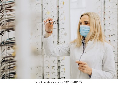 Female Optician Wearing Face Mask And Selling Glasses