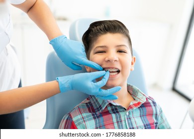 Female orthodontist examining cute boy wearing braces