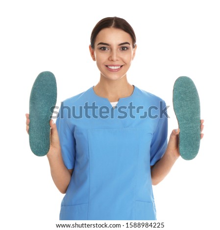 Female orthopedist showing insoles on white background
