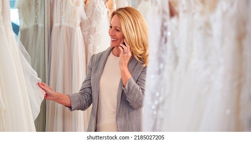 Female Owner Of Bridal Wedding Dress Shop Talking On Mobile Phone