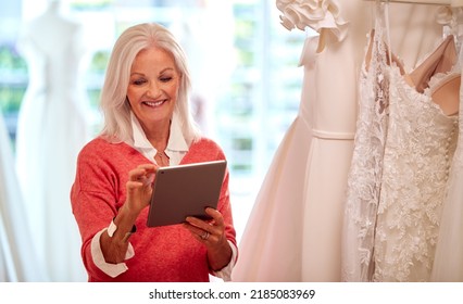 Female Owner Of Bridal Wedding Dress Shop With Digital Tablet