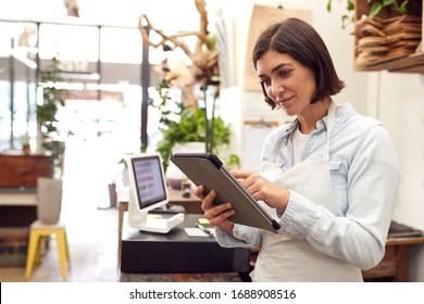 Weibliche Besitzer mit digitalem Tablet, die hinter dem Verkaufsschalter für Floristen stehen