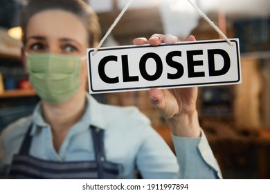 Female Owner Of Small Business Wearing Face Mask Turning Round Closed Sign During Health Pandemic - Shutterstock ID 1911997894