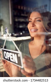 Female Owner Of Start Up Coffee Shop Or Restaurant Turning Round Open Sign On Door