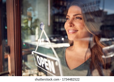Female Owner Of Start Up Coffee Shop Or Restaurant Turning Round Open Sign On Door