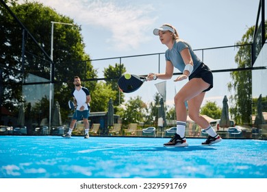 Female paddle tennis player playing mixed doubles on outdoors court. Copy space. - Powered by Shutterstock