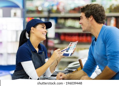 Female Paint Store Worker Talking To Customer Over The Counter