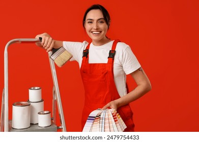 Female painter with color palettes, brush and cans of paint on stepladder against red background - Powered by Shutterstock