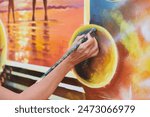 Female painter hand draws picture with paintbrush on canvas for exhibition, close up view of female hand artist painting marvelous picture with small strokes