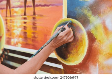 Female painter hand draws picture with paintbrush on canvas for exhibition, close up view of female hand artist painting marvelous picture with small strokes