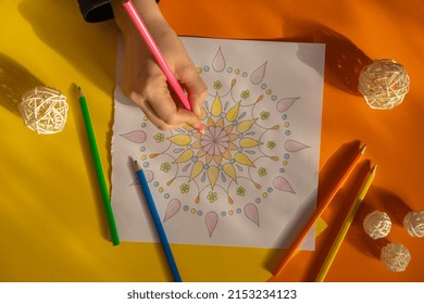 Female painting mandalas antistress page to combat stress. Relaxing hobby mental wellbeing and art therapy. Woman paints sketch, meditative process of coloring pages. Self expression by art 