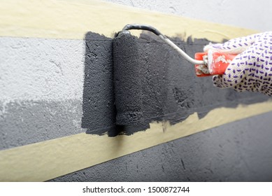 Female Painting A Wall With Masking Tape And Roller