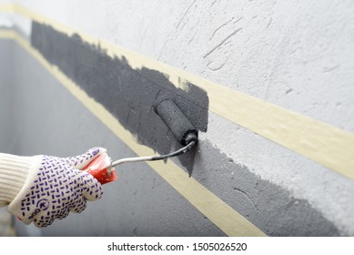 Female Painting A Wall With Masking Tape And Roller