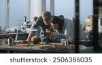 Female paleoanthropologist takes photo of fossil skull remains of extinct human species with colleague archaeologist in archaeological lab using professional camera. Scientist works in the background.