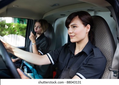 Female Paramedic Team Driving An Ambulance And Talking With Dispatcher On Radio