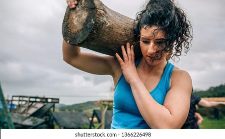 Female participant in an obstacle course carrying a trunk outdoors - Powered by Shutterstock