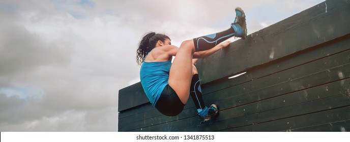 Female Participant In An Obstacle Course Climbing A Wall