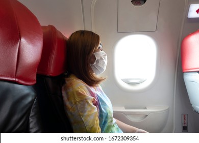 A female passenger traveler wearing mask to protect Corona Virus or Covid-19 and sitting in airplane.