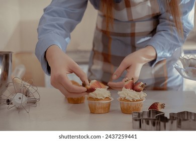 A female pastry chef decorates cupcakes with berries, showcasing her homemade baked goods. Explore the charm of home baking and small-scale business with this image of a skilled baker at work. - Powered by Shutterstock