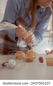 A female pastry chef decorates cupcakes with berries, showcasing her homemade baked goods. Explore the charm of home baking and small-scale business with this image of a skilled baker at work.