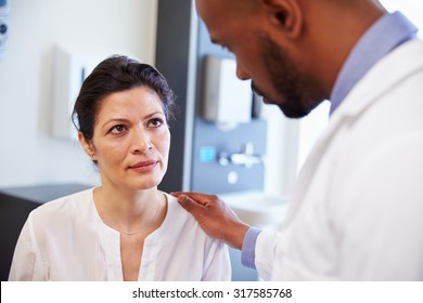 Female Patient Being Reassured By Doctor In Hospital Room