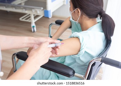 The female patient was being vaccinated by the doctor in her left arm while sitting in a wheelchair. - Powered by Shutterstock