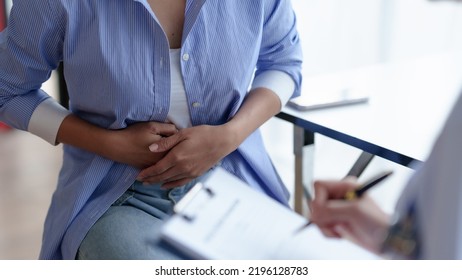 female patient describes abdominal pain สet the doctor know about the symptoms and the doctor takes the patient's history and records it. - Shutterstock ID 2196128783